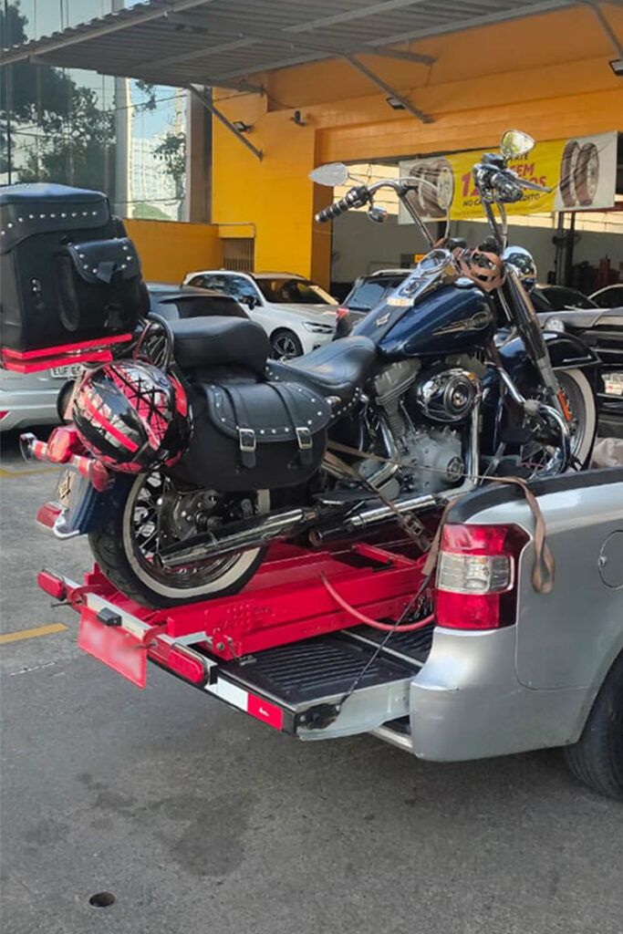 Motorcycle loaded onto a red ramp at the back of a pickup truck