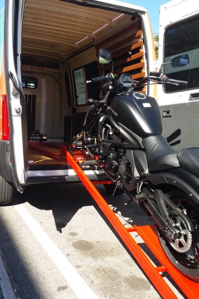 Motorcycle being loaded up an orange ramp into a van